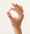Eine rechte Hand hält eine Thiocyn Haarkapsel zwischen Daumen und Zeigefinger. Eine rechte Hand hält eine Thiocyn Haarkapsel zwischen Daumen und Zeigefinger.