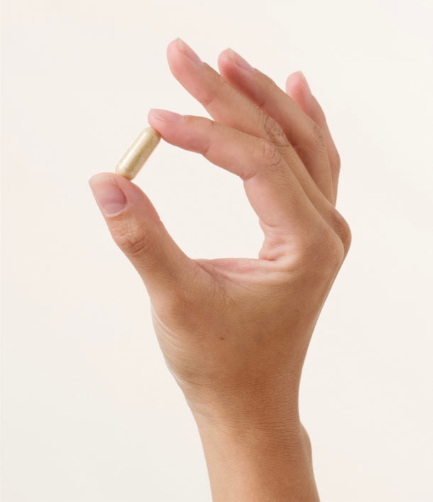 Eine rechte Hand hält eine Thiocyn Haarkapsel zwischen Daumen und Zeigefinger. Eine rechte Hand hält eine Thiocyn Haarkapsel zwischen Daumen und Zeigefinger.