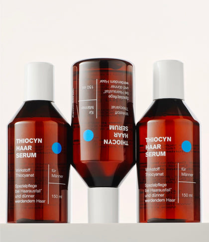 Drei Einzelflaschen des Thiocyn Haarserums Männer. Die erste und dritte Flasche stehen auf dem Flaschenboden, während die mittlere Flasche auf dem Kopf steht. Drei Einzelflaschen des Thiocyn Haarserums Männer. Die erste und dritte Flasche stehen auf dem Flaschenboden, während die mittlere Flasche auf dem Kopf steht.