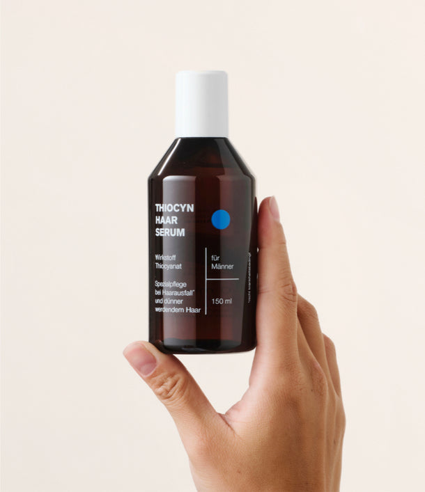 Eine rechte Hand hält das Thiocyn Haarserum Männer in der Einzelflasche senkrecht nach oben. Eine rechte Hand hält das Thiocyn Haarserum Männer in der Einzelflasche senkrecht nach oben.